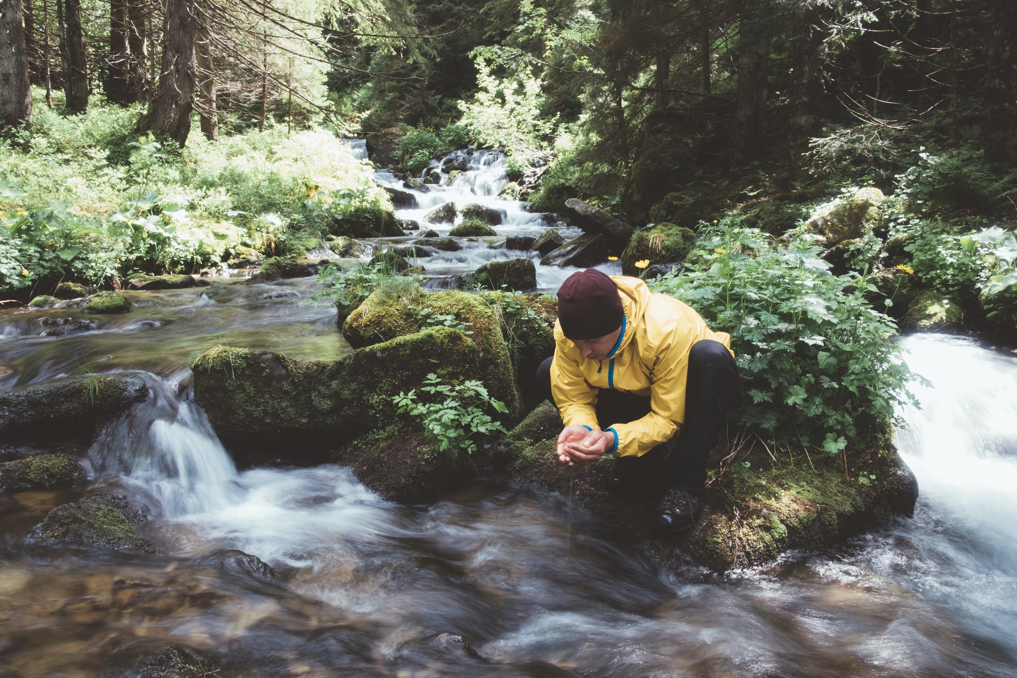 Man drink water from clear mountain stream